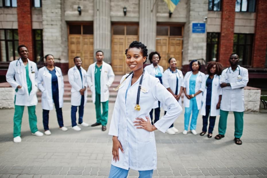 A group of nursing students, including a confident healthcare professional, standing outside a medical training facility, representing CNA bridge programs.